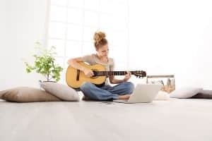 Ear Training For The Guitar - A woman playing guitar and using a laptop.