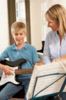Learning Guitar Solos - A photo of a boy getting help from a guitar instructor