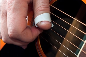 Learn To Play A Guitar Fast – Someone fingerpicking an acoustic guitar