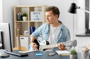 Learn To Play A Guitar Fast – A man using a computer to learn how to play the guitar