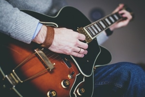 Learn To Play A Guitar Fast - Someone playing an electric guitar in the sitting position