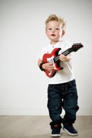 Learn To Play A Guitar Fast – A small boy playing a guitar