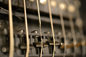 Fix Guitar String - A photo of an electric guitar string, broken at the bridge