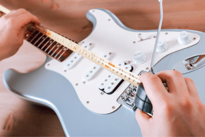 Fix Guitar String - A photo of someone setting the intonation on an electric guitar