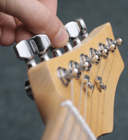 Fix Guitar String - A photo of someone tuning an electric guitar