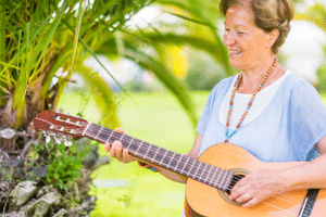 Learning Guitar For Seniors - A woman enjoying her guitar outdoors.