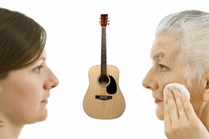 Learning Guitar For Seniors - A photo of a younger and an older woman with an acoustic guitar in between them.