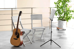 How To Store A Guitar – An acoustic guitar on the floor and leaning against a chair. 