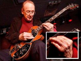 Playing Guitar With Arthritis -  A photo of Les Paul playing his guitar on stage.