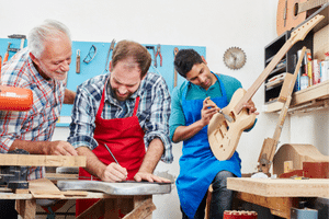 Buying A Guitar In A Guitar Store – Workers designing and building guitars in a shop.