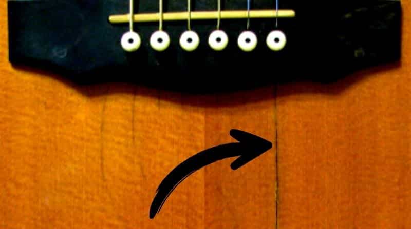 How Guitar Cracks Affect The Sound - An acoustic guitar body with a crack in the soundboard